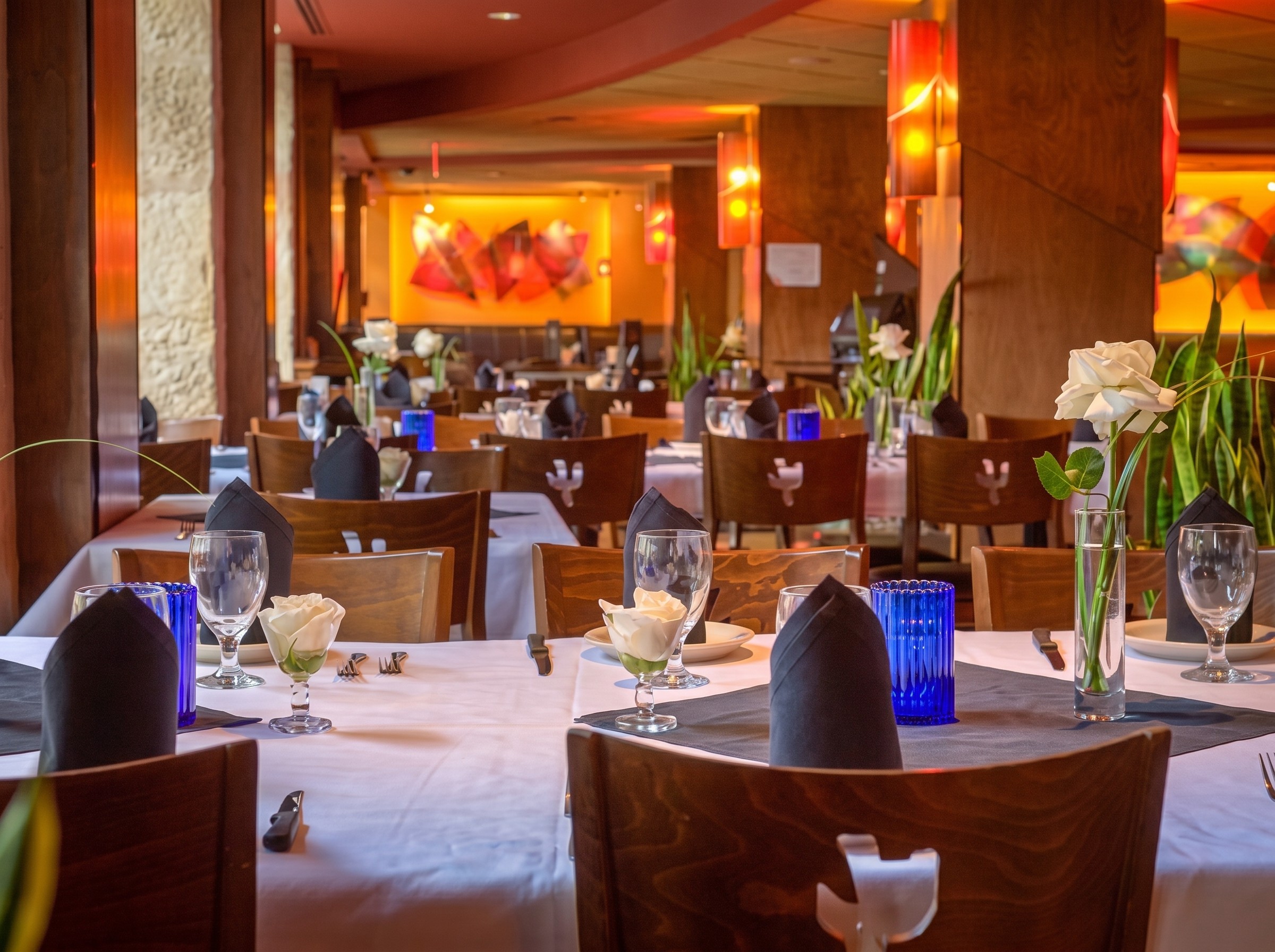 Upper Dining area at Iron Cactus San Antonio set with white linens, black napkins and blue glassware, overlooking the River Walk