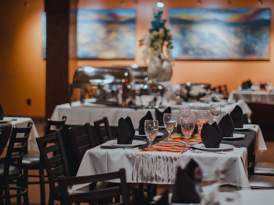 The Agave Room at Iron Cactus San Antonio set for a private event with white linens, black napkins, serape runners and a buffet line