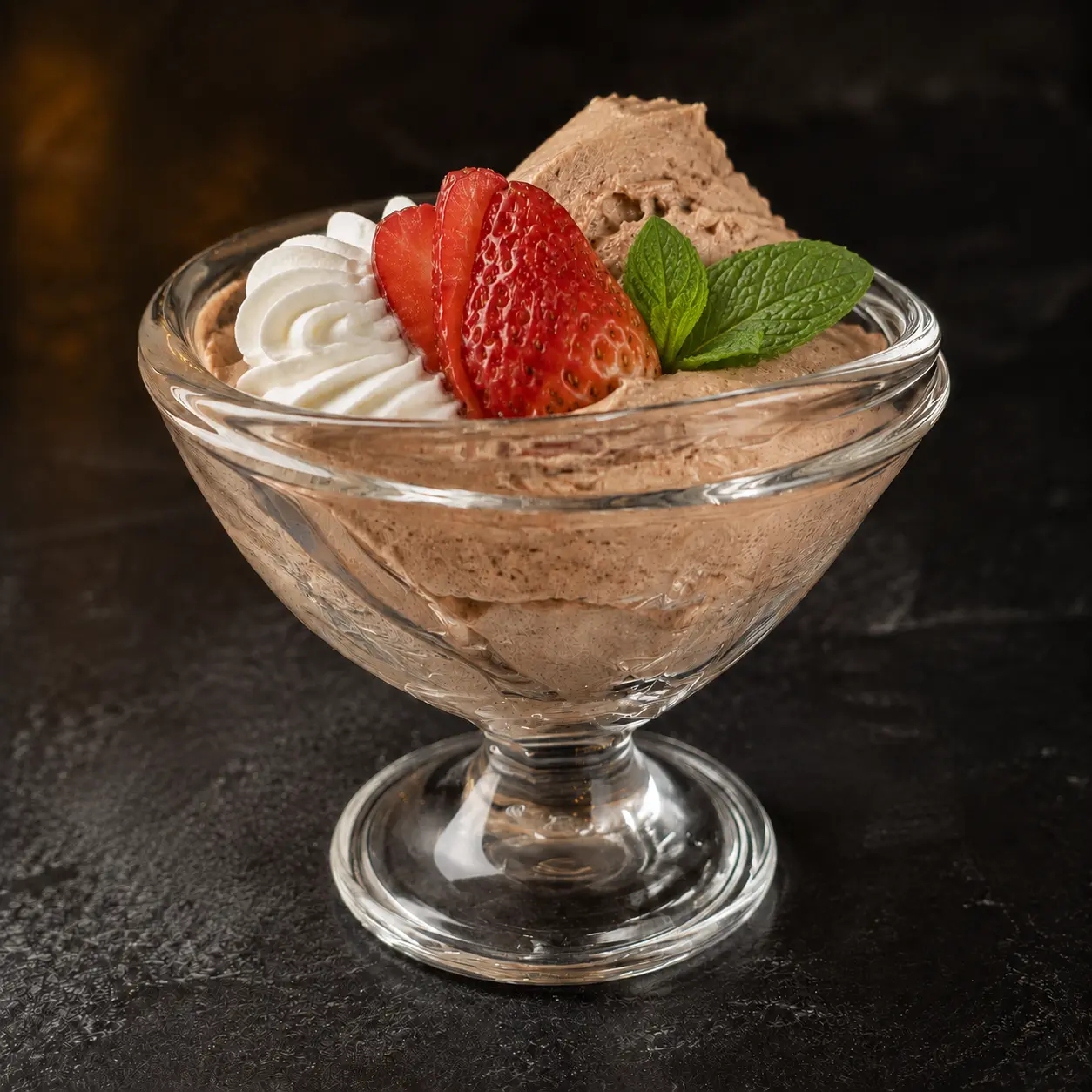 Mexican chocolate mousse served in a shallow stemmed glass chalice, topped with whipped cream, sliced strawberry and fresh mint at Iron Cactus