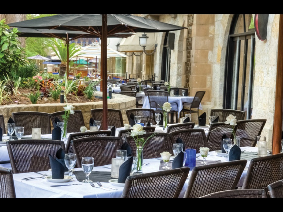 The River Walk Patio at Iron Cactus San Antonio set for a private event with white linens, black napkins and umbrellas