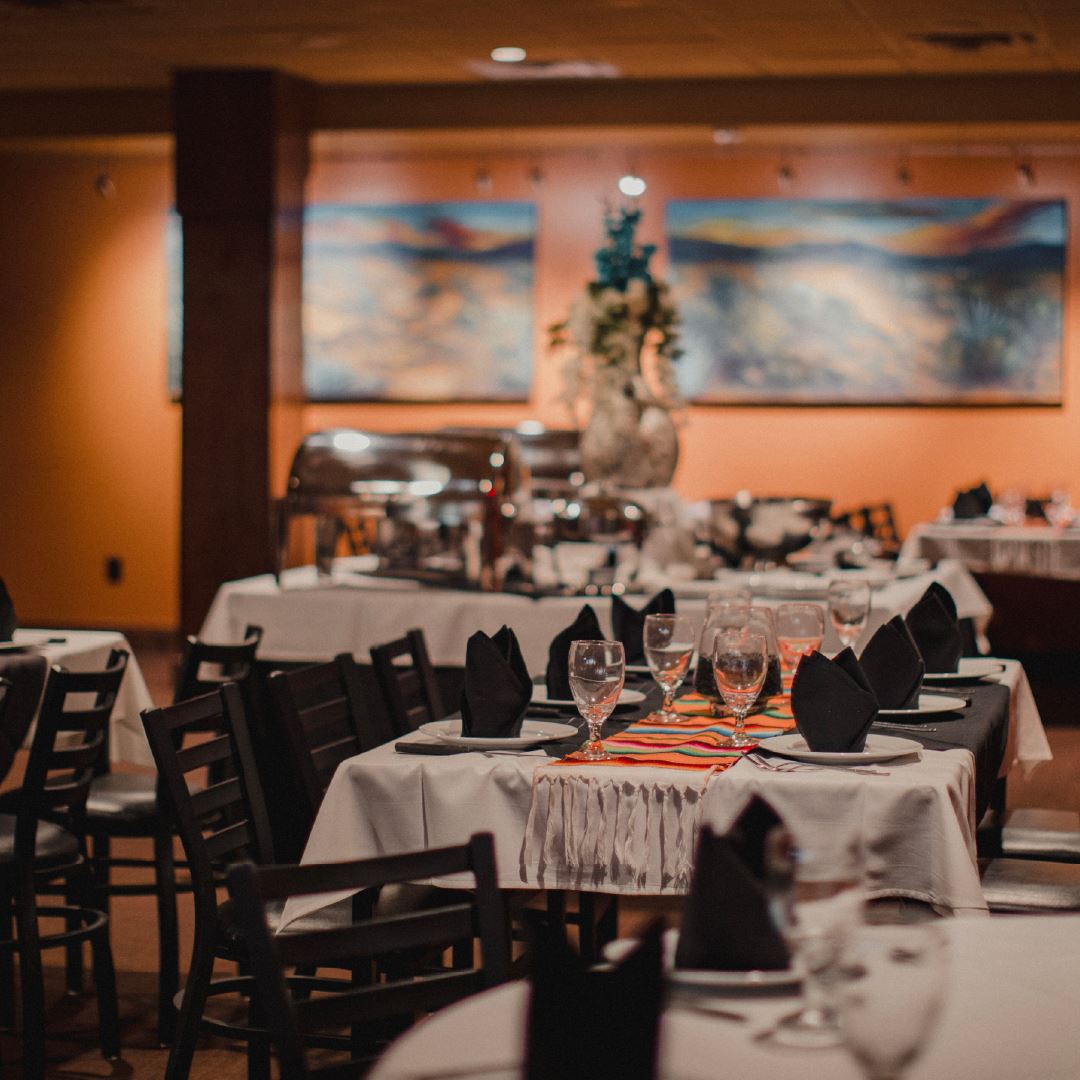 Long banquet tables set with white linens, black napkins and Mexican serape runners in the private dining area at Iron Cactus on the San Antonio River Walk