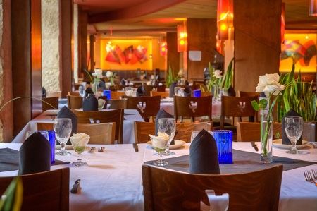 White-linen dining room with folded black napkins, blue glassware and fresh roses at Iron Cactus San Antonio