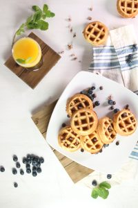 a white plate topped with blueberries and waffles