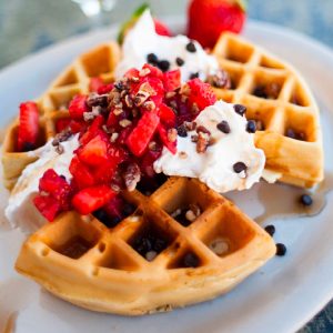 a waffle topped with whipped cream and strawberries